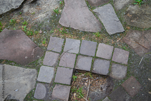Fotografie Texture of old stone pavement walkway with green moss close up, flagstone garden path background with granite cobblestone border curb, rustic landscape design full frame top view mockup