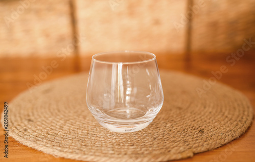 Empty clear water glass on a round coaster on a wooden table