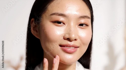 Woman applying skincare cream on face with closed eyes