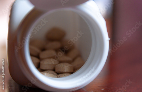 Pills spilling out of a bottle isolated on dark background, Vitamin for health