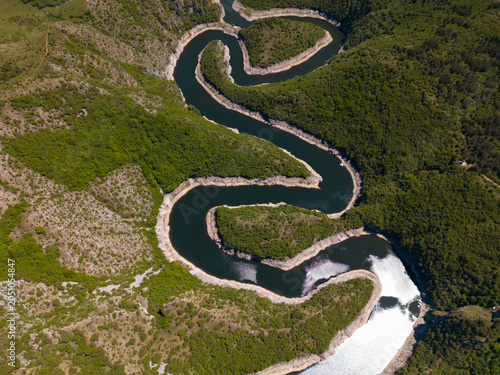 High angle aerial view of the famous Uvac River meanders canyon in Serbia. Stunning drone landscape of curvy river flowing through deep rocky cliffs and green hills.