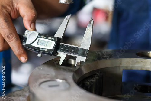 Schilderij op canvas A technician uses a digital vernier caliper to measure the internal diameter of a hole on a heavy metal planetary carrier component