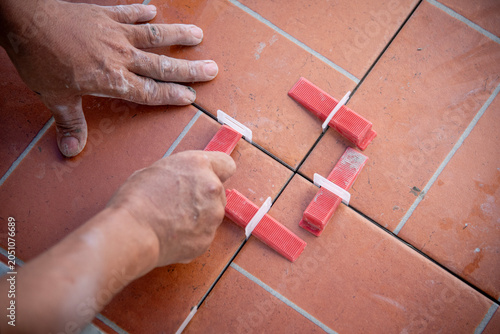 Bild auf Leinwand Professional tiler placing terracotta ceramic tiles on a floor with adhesive mortar