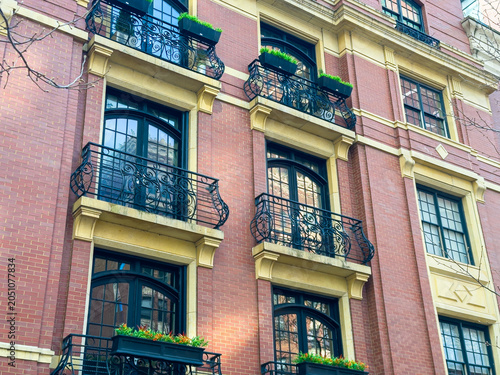 Foto Red brick building with black iron balconies in an urban setting on a clear day