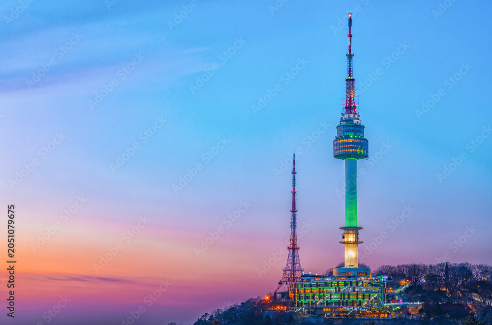 Obraz premium Beautiful twilight night view of the illuminated N Seoul Tower glowing green on Namsan mountain under a vibrant pastel sunset sky, Seoul, South Korea.