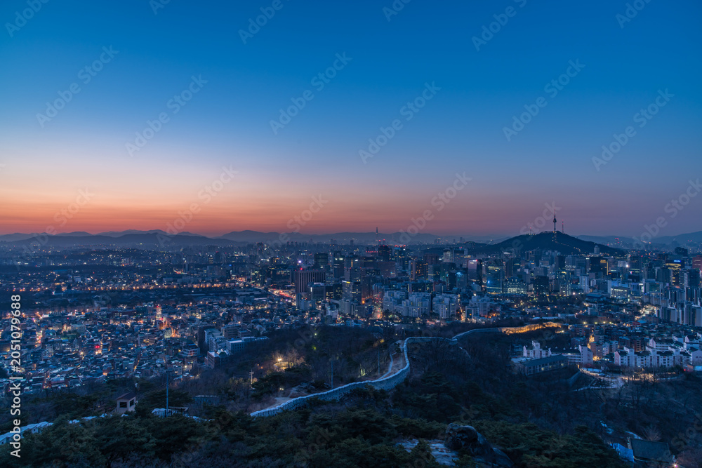 Fototapeta premium Stunning twilight sunset over Seoul city with the illuminated ancient Seoul City Wall on Inwangsan mountain and N Seoul Tower on Namsan in the background, South Korea.
