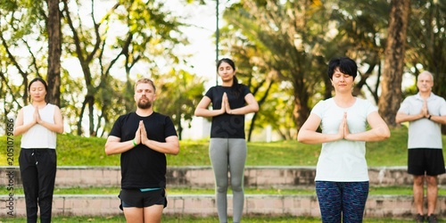 Obraz na płótnie Group of diverse adults practicing yoga outdoors in a serene park setting