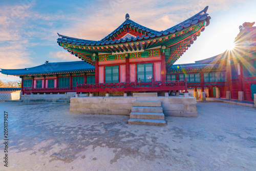 Bild auf Leinwand Beautiful sunset view of traditional Korean architecture inside Gyeongbokgung Palace, featuring a brilliant sunburst flare glowing over the ancient wooden pavilion, Seoul, South Korea