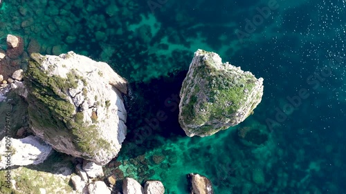An aerial view of Birds soar over the turquoise waters below Bonifacio's limestone cliffs, where waves crash against the rugged coastline in France