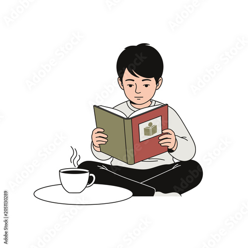 Young boy sitting cross legged reading a book with a steaming cup nearby