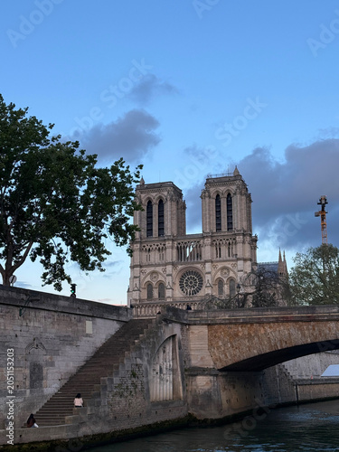 The iconic towers of Notre Dame de Paris Cathedral viewed from the Seine River with a bridge. Paris, France