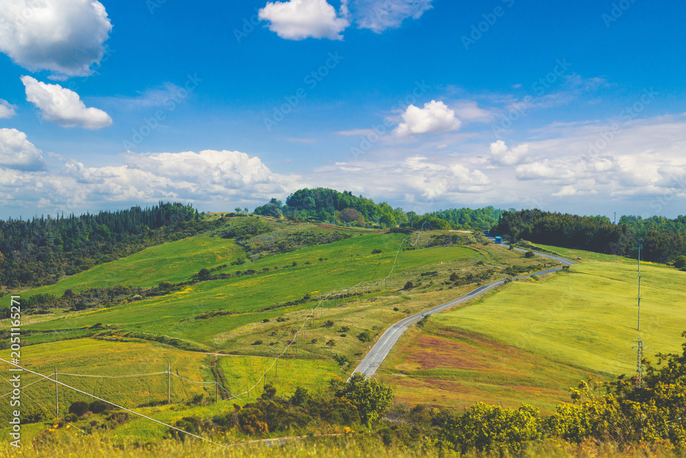 Fototapeta premium Beautiful spring landscape. Landscape with mountains and valley on a sunny day. View from above of sunny fields on rolling hills in Tuscany, Italy