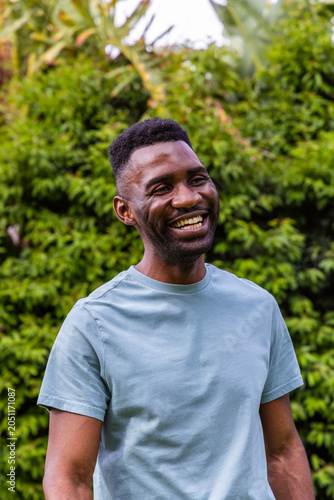 African American man smiling and standing in garden wearing light blue crew-neck T-shirt