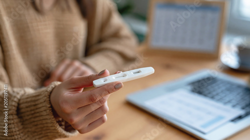 A person holds a pregnancy test beside an open calendar, suggesting home planning and emotional anticipation.