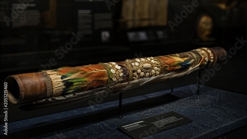 An ornate ceremonial blowpipe displayed in a museum case.
