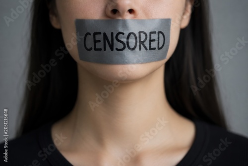 Woman with tape over mouth labeled censored. Concept of censorship, silencing voices, freedom of speech, suppression, discrimination and human rights