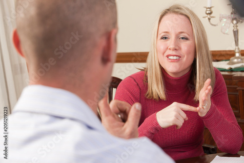 Woman signing the word 'Afford' in American Sign Language while communicating with a man