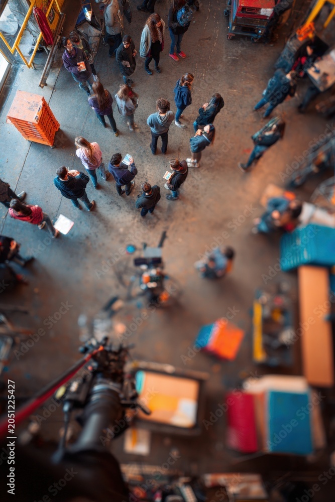Obraz premium People standing in a spacious workshop or warehouse. Group of man and woman participating in a community project or creative event. High angle view of individuals in an industrial area.