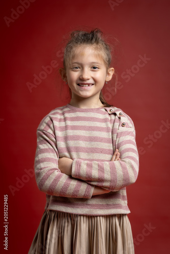 Smiling Little Girl Posing in Studio. Full Length Child Portrait with Playful Expression and Fashionable Clothing