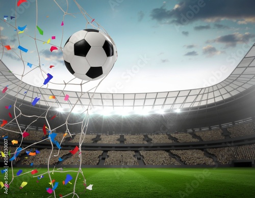 A soccer ball sails into the net amidst a shower of colorful confetti, set against the backdrop of a grand stadium with illuminated seating under a dramatic sky.