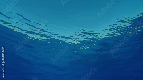 View from below of crystal clear blue surface of the water with fine ripples against turquoise sky during doldrums. Natural underwater background of water surface in calm weather