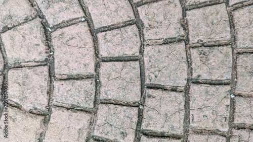 Top view of weathered concrete pavement with a curved block pattern and cracked texture.