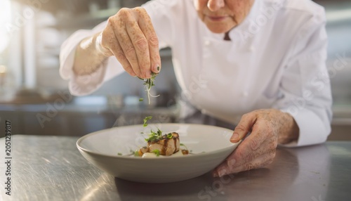 Chef Sprinkling Fresh Herbs on Gourmet Dish in Professional Kitchen Setting with Attention to Detail