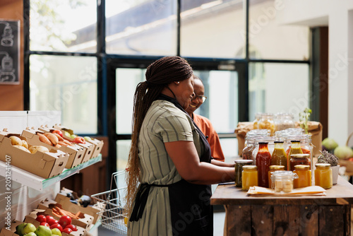 Foto African American merchant stands in her eco-friendly store, offering freshly harvested bio food products to customers, female vendor catering to customer, showcasing her sustainable organic items