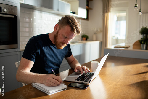 Man working on laptop at home kitchen table