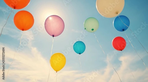 Colorful balloons float in the sky during a sunny day with clear blue skies and few clouds