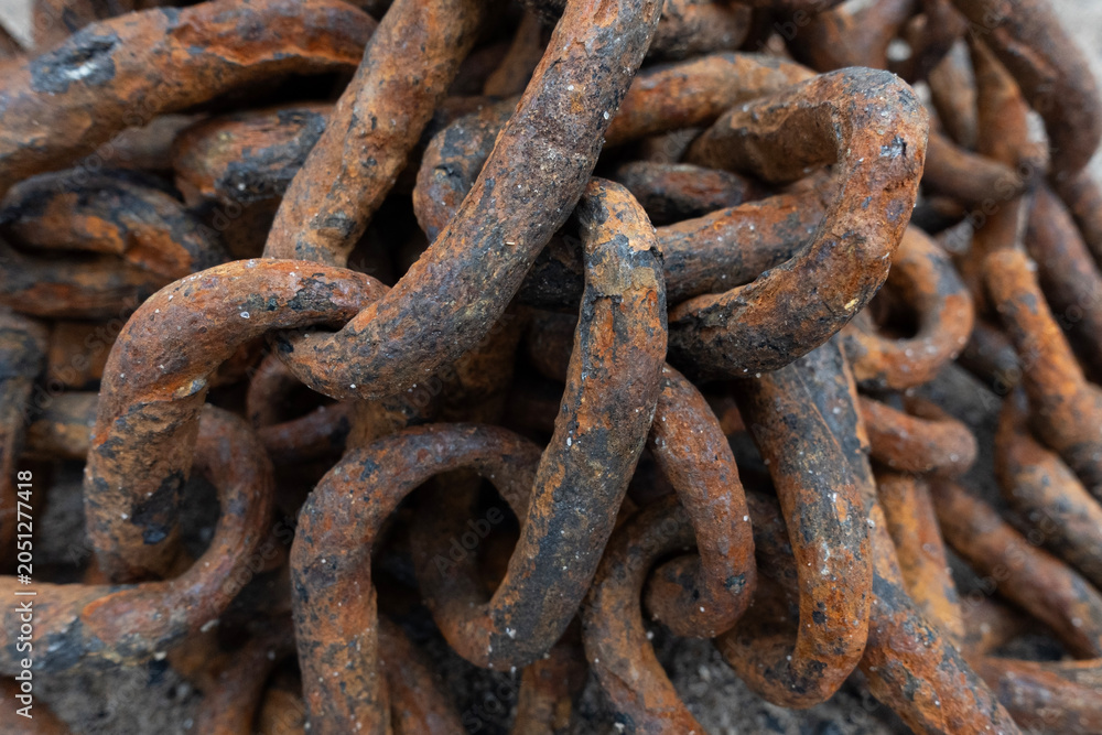 Fototapeta premium Close-up of a heavy rusty iron chain tangled in a pile on a ground