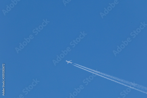 twin engined jet liner aircraft with contrails, in flight at high altitude, clear blue sky