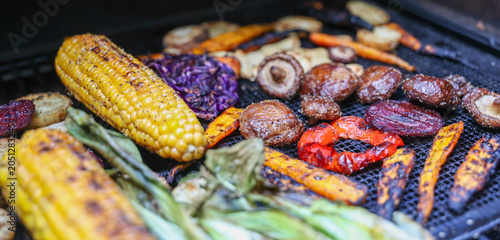 Farm fresh garden vegetables cooking on a pellet grill smoker for a vegetarian dinner. The healthy food is colorful and packed with vitamins and garden nutrients. Delicious!