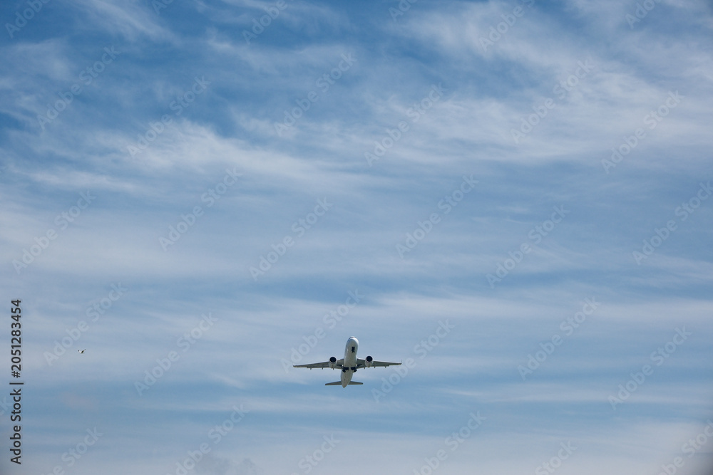 Fototapeta premium Front view of a commercial jet airplane climbing after takeoff against blue sky with white clouds