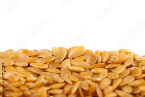 Plie of golden raw flax seeds on a white background