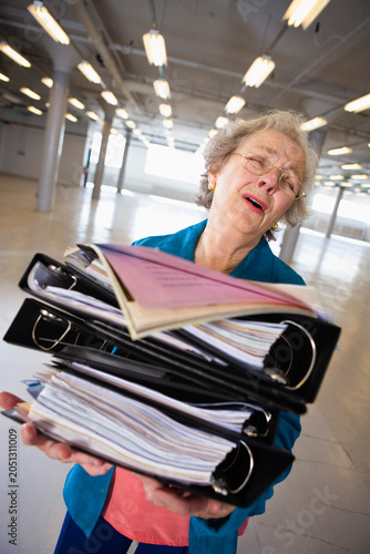 View of a senior woman carrying heavy files