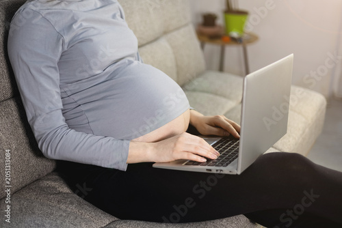 Woman working on laptop during pregnancy. Close up.