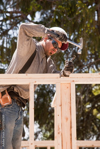 Carpenter hammering a pry bar to adjust studs