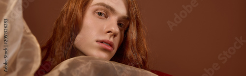 Bild auf Leinwand Elegant young man with long red hair showcases fashion and charm in a stunning p