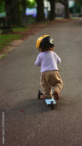 Obraz na plátně Toddler pushing scooter away along park road gaining confidence independence and