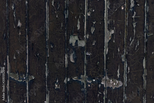 Texture of old vertical weathered wooden planks with cracked and peeling dark paint as background