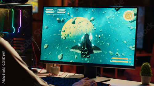 Foto Man using gaming keyboard to fly spaceship in SF videogame, close-up on computer screen, gamer using powerful PC and computer peripherals to compete in science fiction multiplayer game tournament