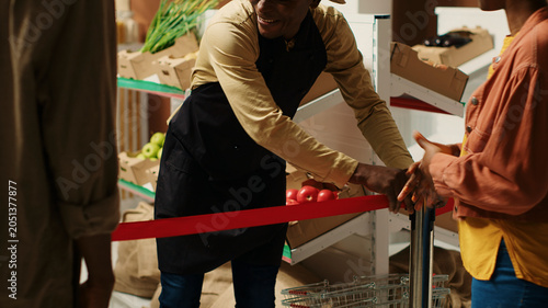 Fotografi Local merchant opening grocery store doors and welcoming clients, greeting people with new organic homegrown fruits and vegetables, African American vendor selling eco friendly food items