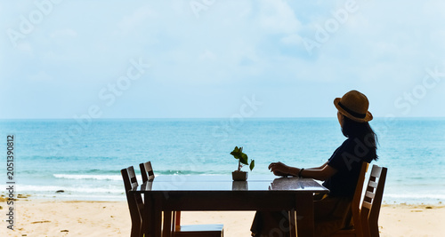 Fényképezés Single Asian young woman sits at dining table by window on tropical beach at Ao
