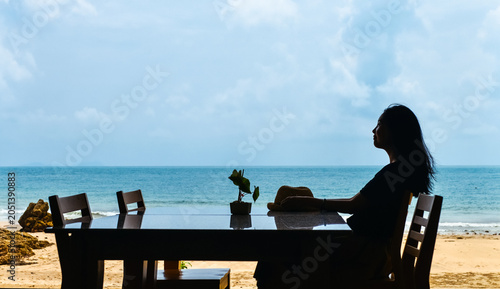 Konstfotografi Single Asian young woman sits at dining table by window on tropical beach at Ao