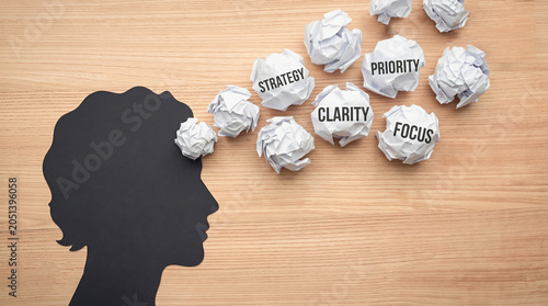 Head releasing crumpled paper with words strategy, priority, clarity, and focus. Represents mindfulness and clear thinking