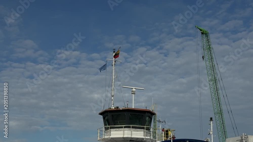 Ship bridge and harbor crane under cloudy sky