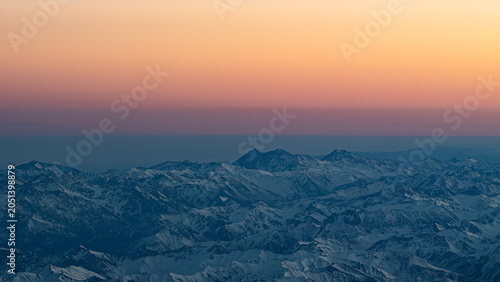 Картината върху платно Snow capped mountains at dusk seen from a high altitude flight