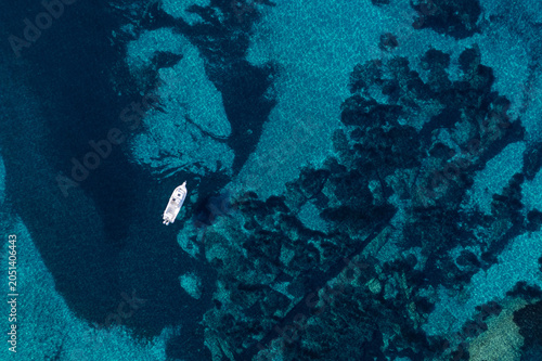 Aerial view of a sailing boat in the blue sea, Corsica, France.
