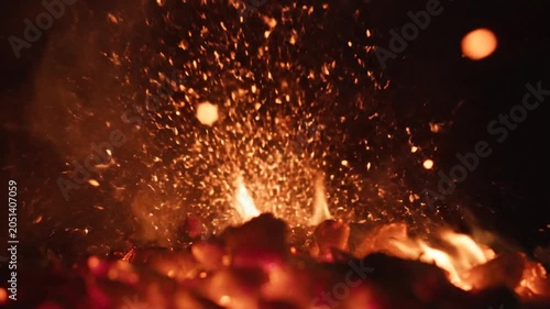 Glowing embers, burning fire sparks, warm flames, nighttime blaze